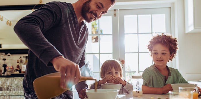 Papá sirviendo leche a sus hijos para que tengan una alimentación saludable para niños