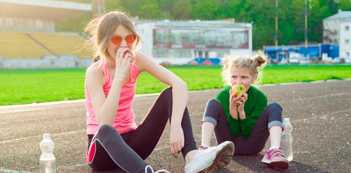 Niñas sentadas en la pista comiendo manzana