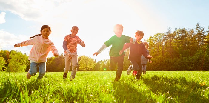 Niños corriendo en el parque con el sol de fondo