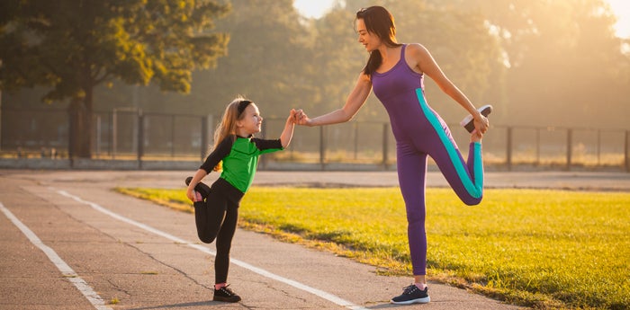 Mamá estirando con su hija entendiendo la importancia de tener bienestar físico