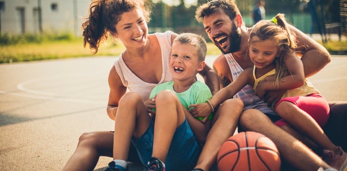 Familia unida sonriente en una cancha después de jugar baloncesto