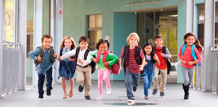 Niños corriendo para ingresar al colegio después de un desayuno nutritivo