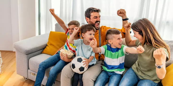 Familia viendo y celebrando un partido de fútbol en casa