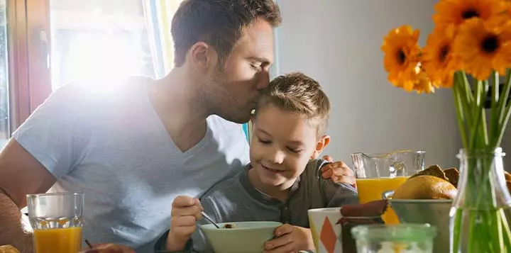 Padre realizando receta de desayuno a su hijo