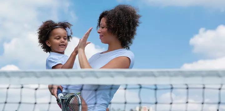 Niña practicando tenis junto a su madre 