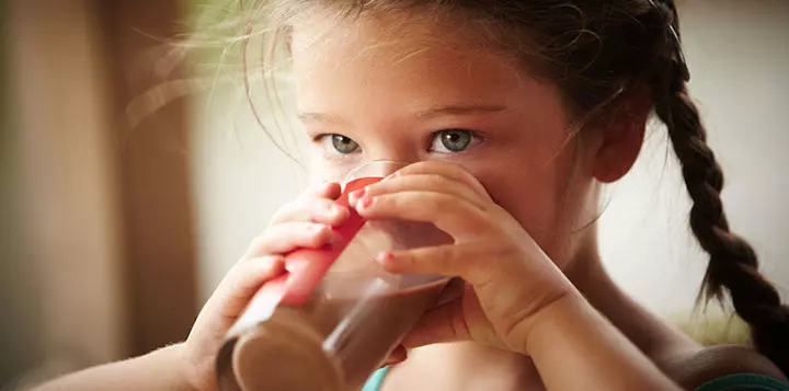 Niña tomando un vaso de leche de chocolate 