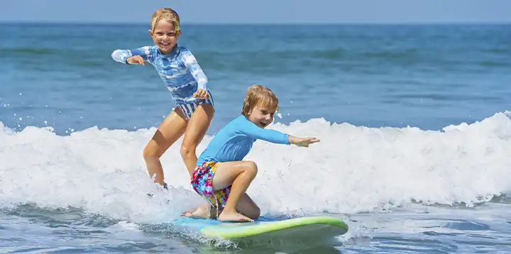 Niños felices surfeando en el mar como deporte acuático   