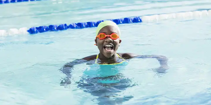 Niña feliz practicando la natación como deporte acuático  