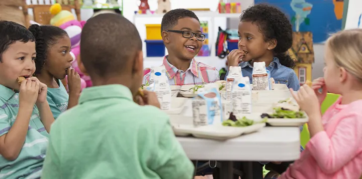 Niños tomando su merienda en el salón de clases