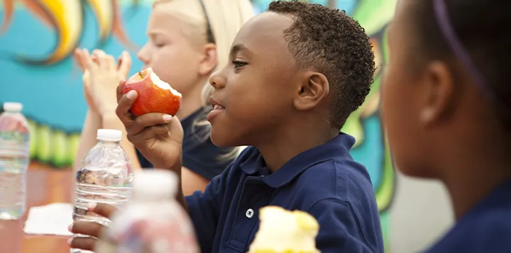 Niño comiendo una manzana y bebiendo agua como merienda  