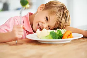 Niño toma una comida saludable para la noche que es balanceada, adecuada y suficiente