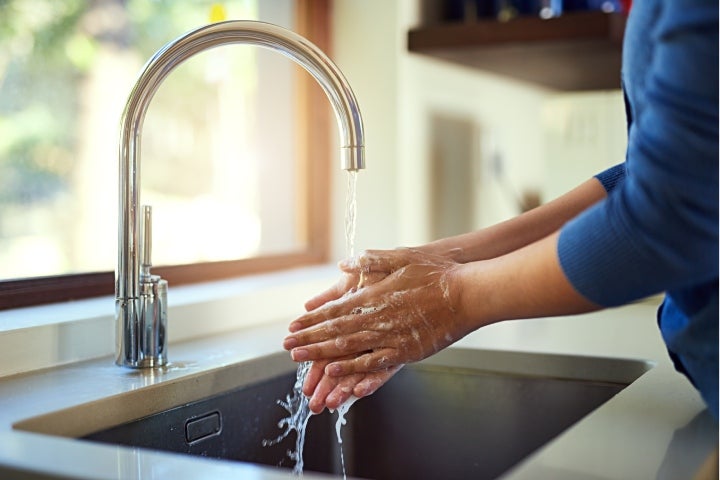 Mujer lavándose las manos mientras ahorra agua
