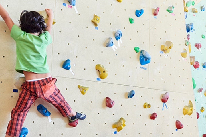 Niño escalando en un muro didáctico