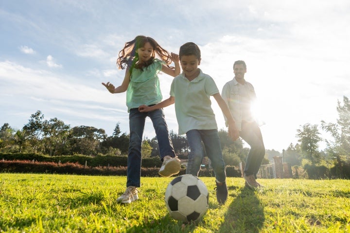 Niño y niña jugando fútbol junto con su padre