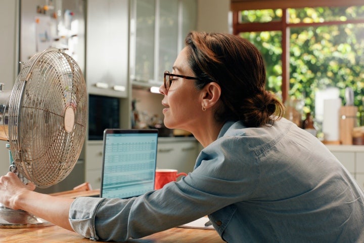 Mujer disfrutando aire fresco en casa gracias al uso eficiente de energía.