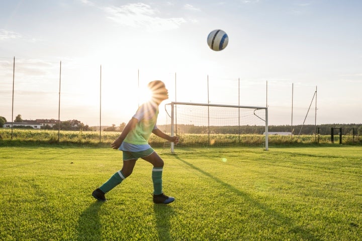 Joven dominando el balón sin dejarlo caer como juego predeportivo de fútbol.