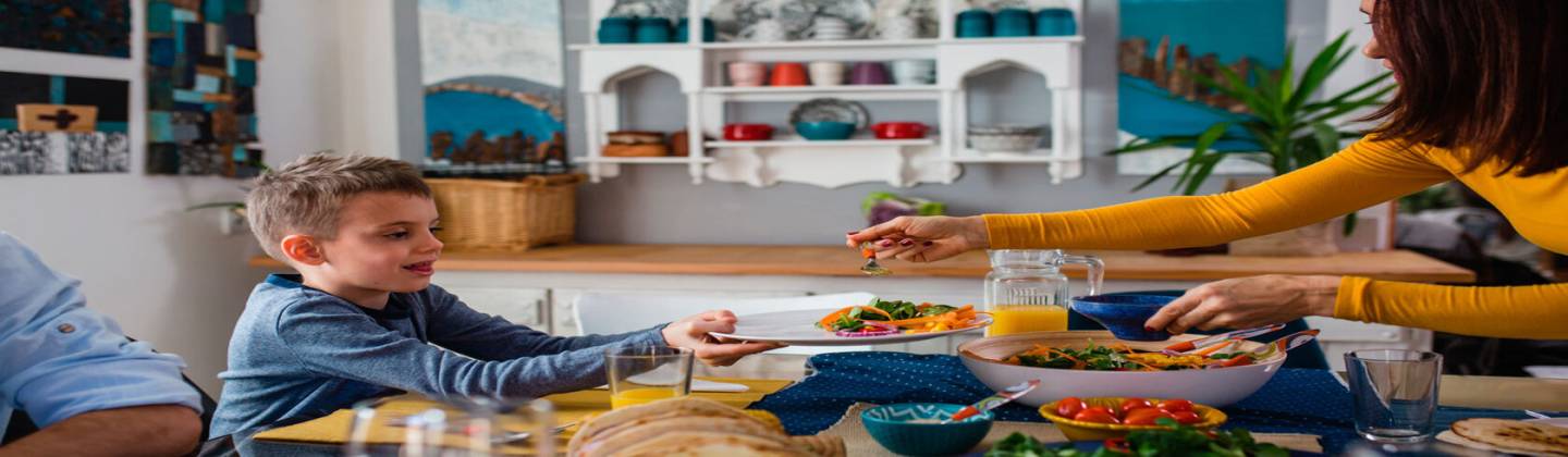 Mamá sirviéndole comida a su hijo para que tenga una dieta saludable