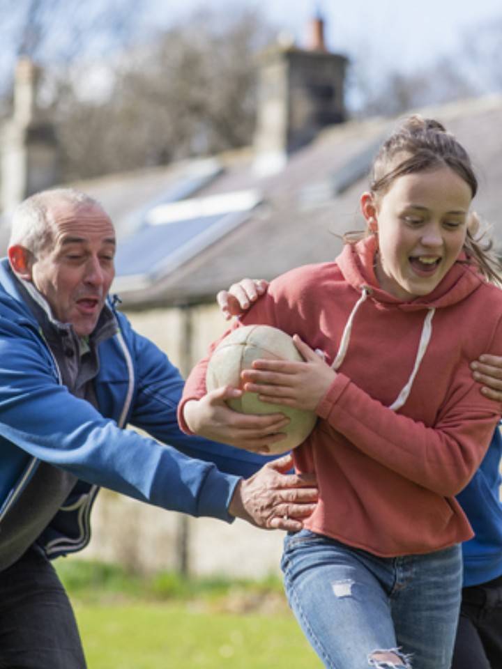 Adulto jugando con dos niños balonmano