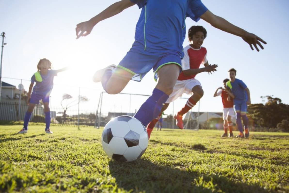 Niños felices jugando fútbol con deporte en equipo
