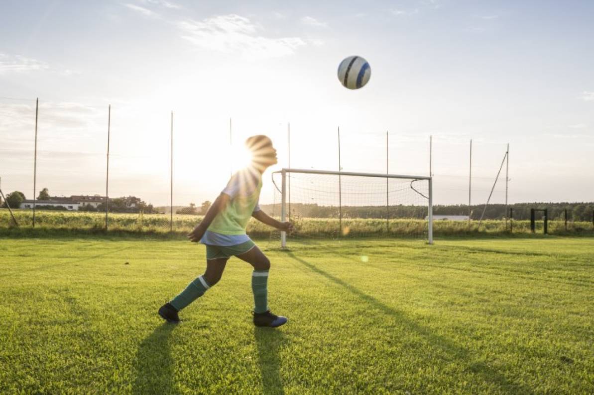 Niño practicando fútbol en una cancha