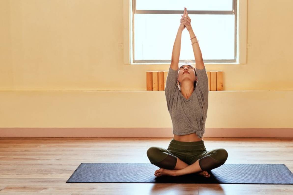 Mujer haciendo yoga desde la comodidad de su sala.