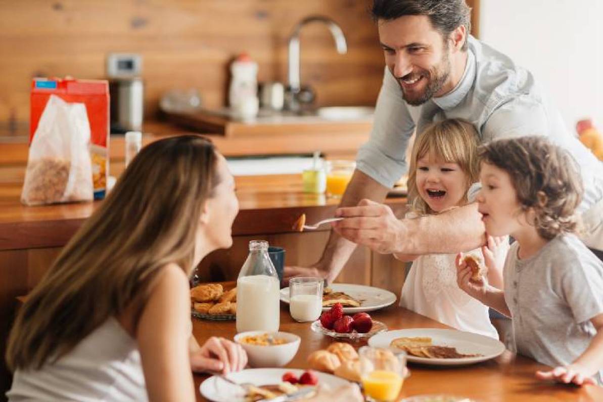 Mamá, papá e hijos sonriendo y disfrutando de desayunos internacionales